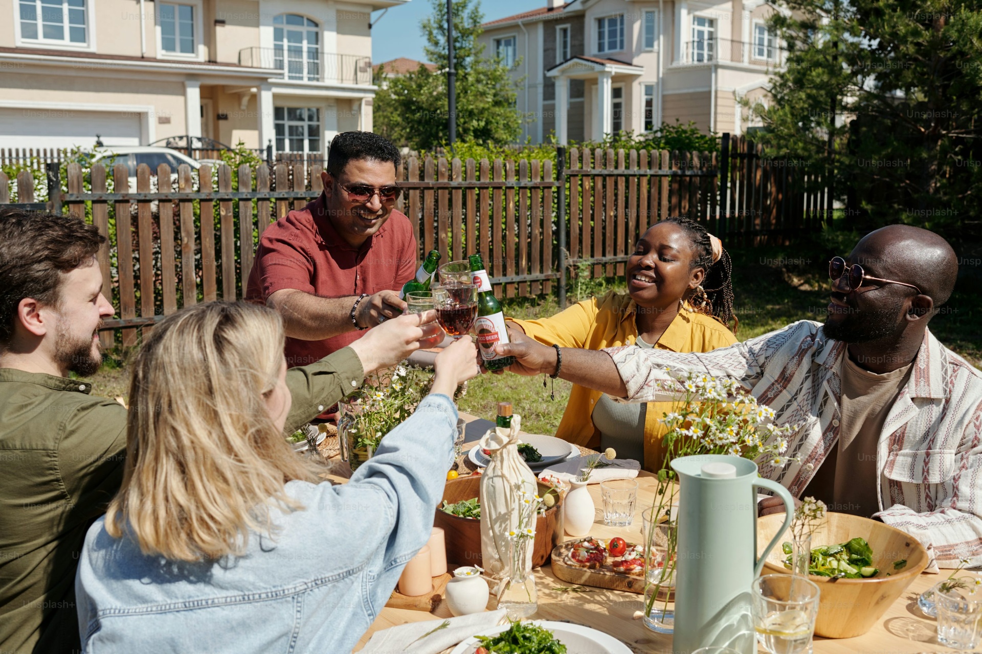 Seven diverse guests around a long candlelit dinner table mid-laugh at a curated Synq dinner